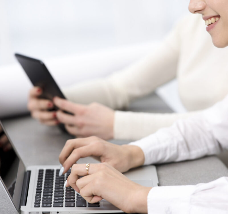 smiling-young-businesswoman-typing-laptop-desk